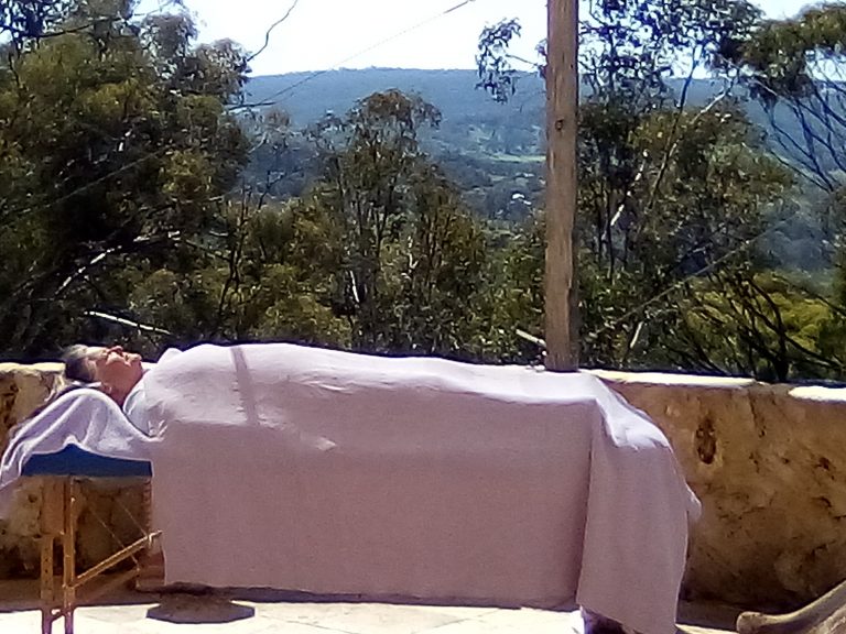 woman laying down on a Reiki table in the middle of Nature